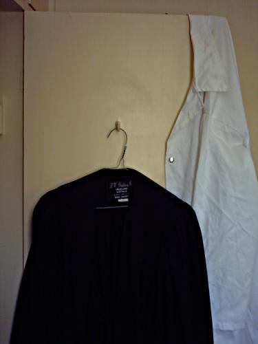 A lab coat and an academic gown hanging up on a door